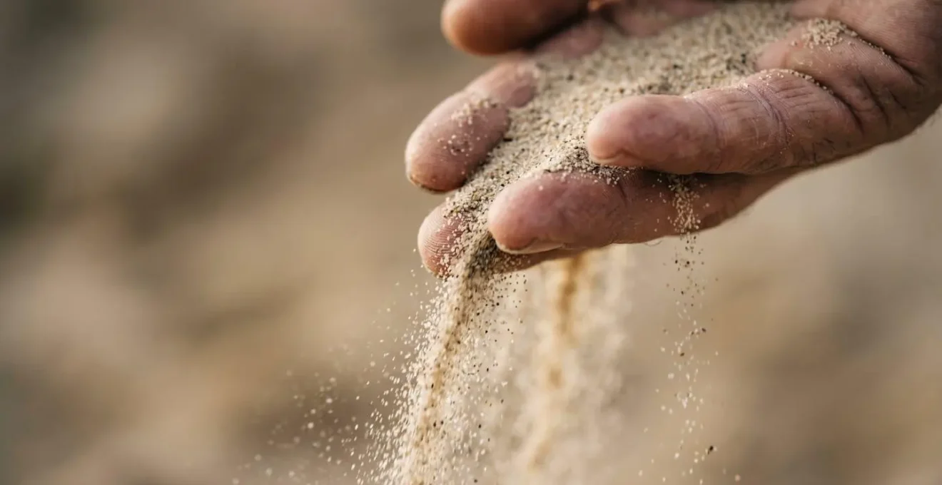 A close-up of a hand with fine sand slipping through the fingers, symbolizing how lifestyle inflation erodes financial resources and savings potential.