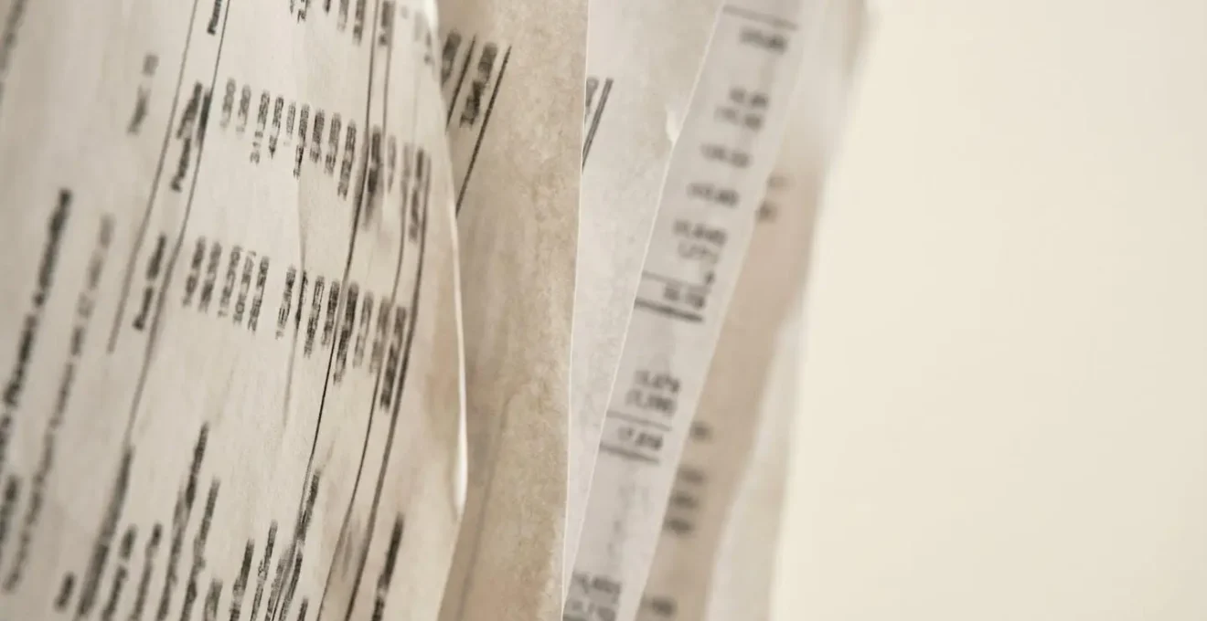 Close-up macro photograph of layered financial documents showing property expense breakdown and yield calculation methodology